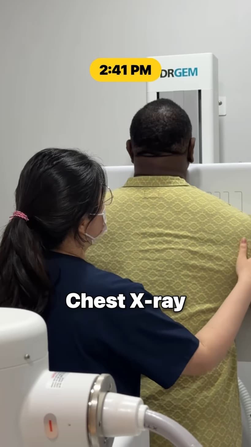A radiographer positioning Chef Rush against a chest X-ray panel.