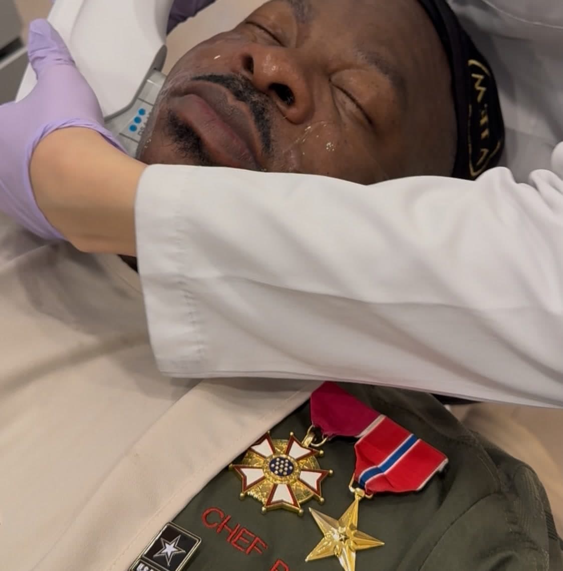 A patient reclined in a treatment chair while a clinician in gloves works on their face.